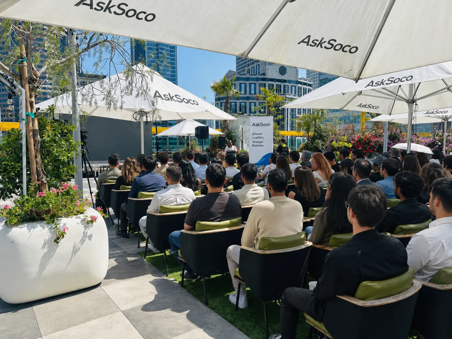 Audience seated under AskSoco-branded umbrellas at an outdoor industry event.